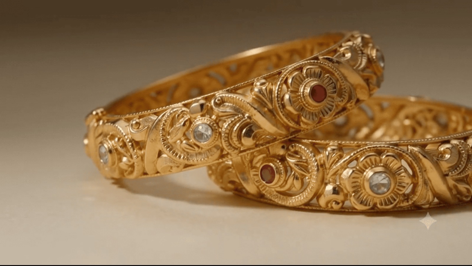 Close detail of engraved gold bangles with ruby and white stone settings